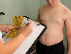 Anak laki-laki kelebihan berat badan berkonsultasi dengan dokter / iStockphoto