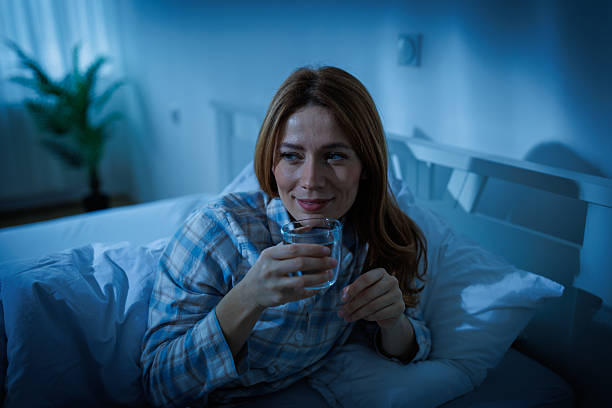 Seorang wanita sedang minum air putih sebelum tidur / iStockphoto